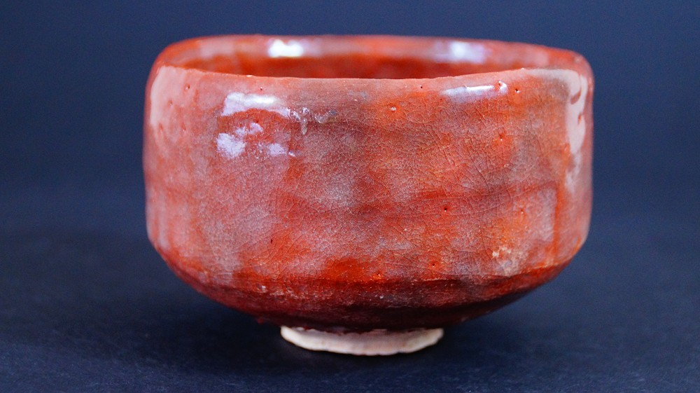 Additional side view of the chawan made of Raku ware by Sairi Hotoku with iridescent red glaze