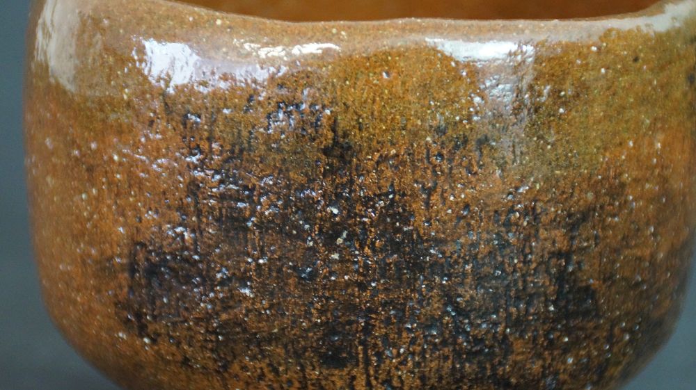 Extreme close-up of the textured honey-brown glaze of the chawan made of Ohi ware