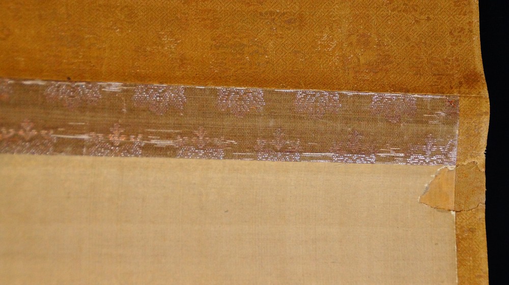 Detail of the golden-brown brocade mounting with silver pattern band of the hanging scroll