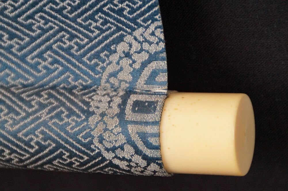 Detail view of the scroll end with ivory finial and blue brocade silk of the hanging scroll Japanese Eggplant