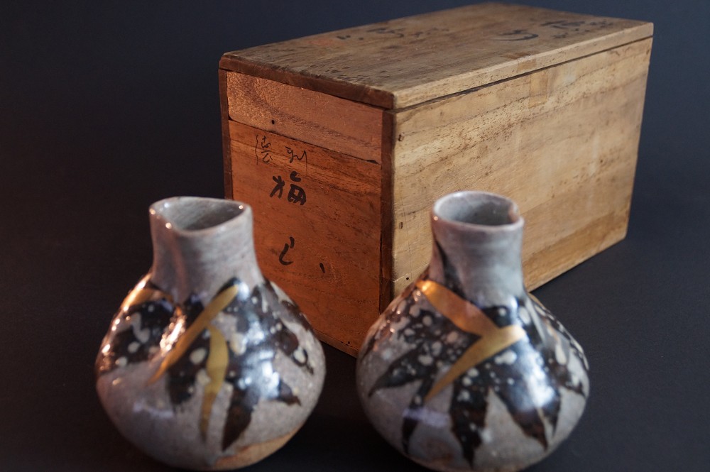 The two sake bottles in front of the signed storage box with calligraphy