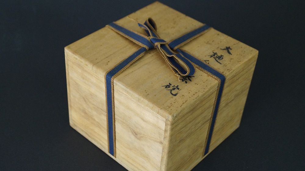 Geschlossene, mit Band verschnuerte Aufbewahrungsbox der Chawan Teeschale aus Raku-Keramik