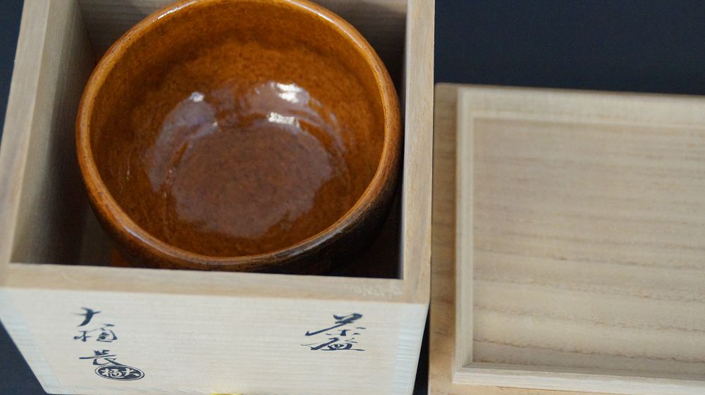 Chawan Teeschale in der geoeffneten Aufbewahrungsbox neben dem beschrifteten Kastendeckel
