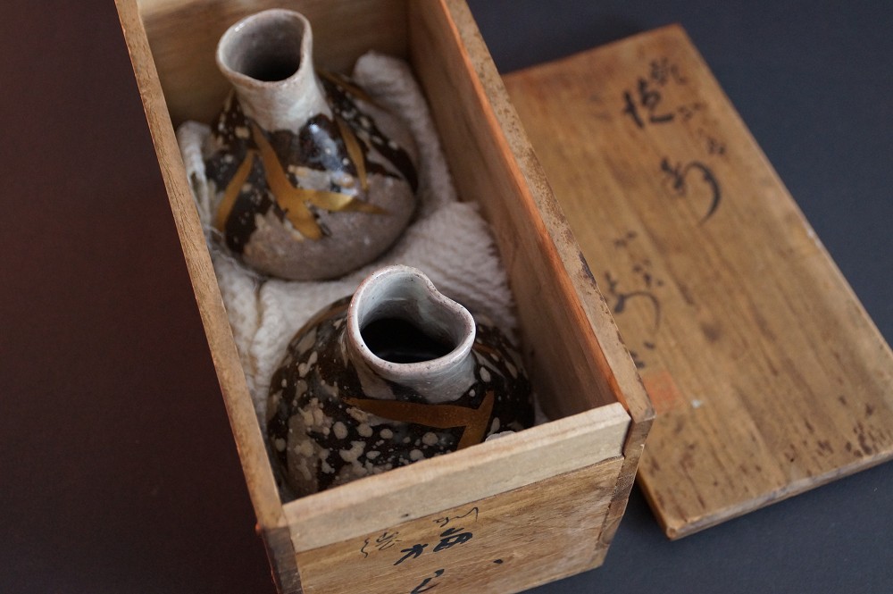 The two sake bottles nestled in white padded cloth in the opened storage box