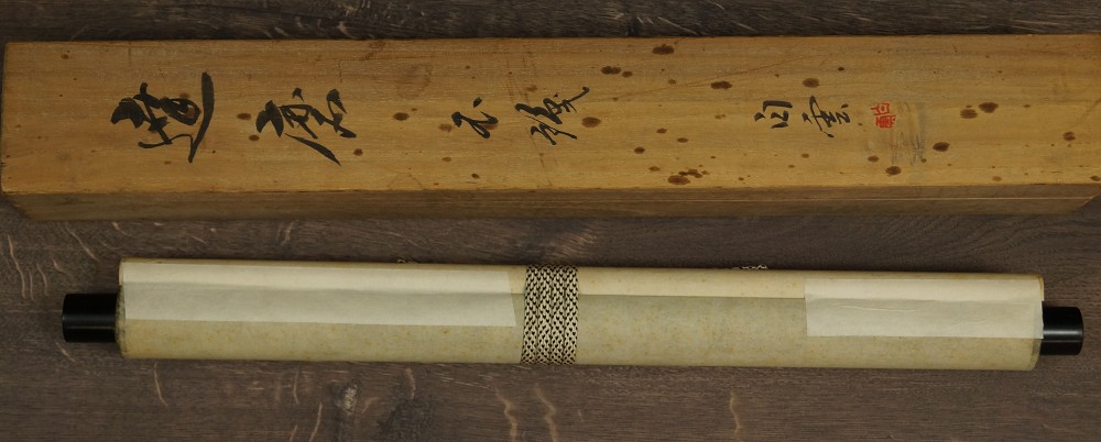 Rolled Up Hanging Scroll Next to Labeled Wooden Box