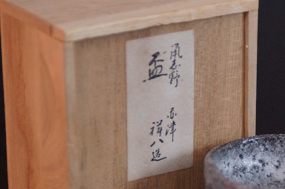 Close-up of the paper label bearing the inscription Shino and the potter's name