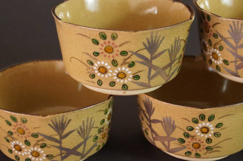 Close-up of several bowls with hand-painted bamboo and chrysanthemum motif