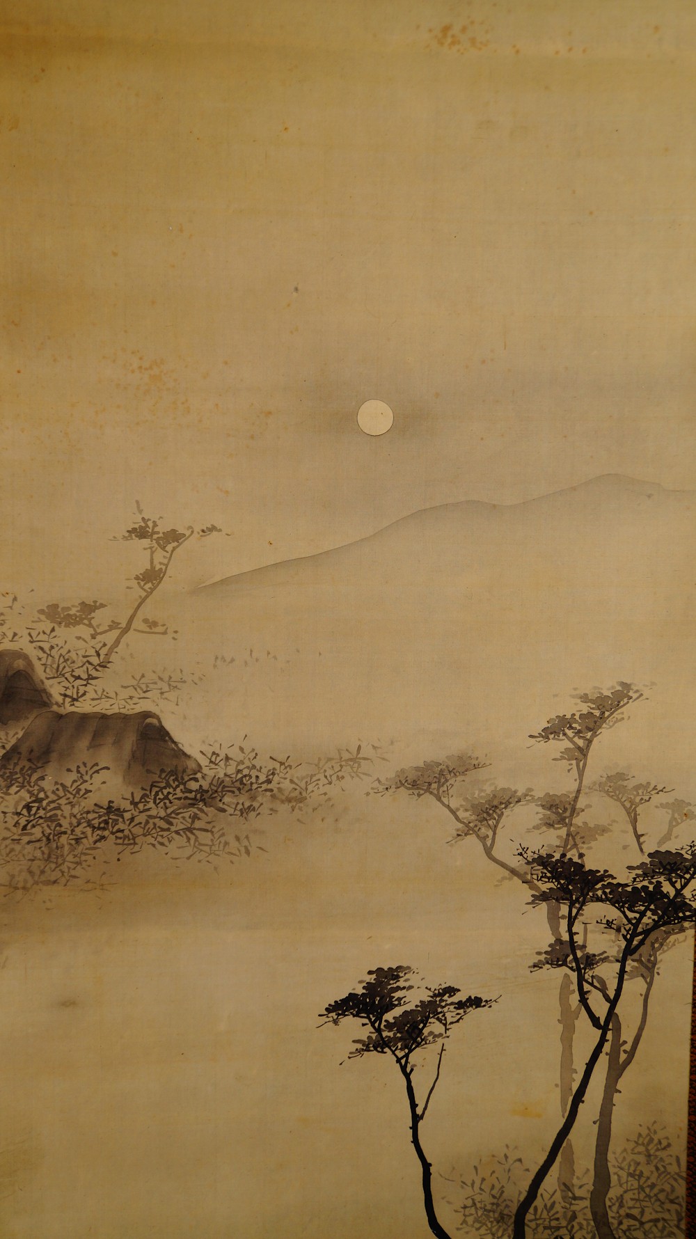 Nahaufnahme der nebligen Berglandschaft mit Mond, Felsen und Baeumen von Naoun