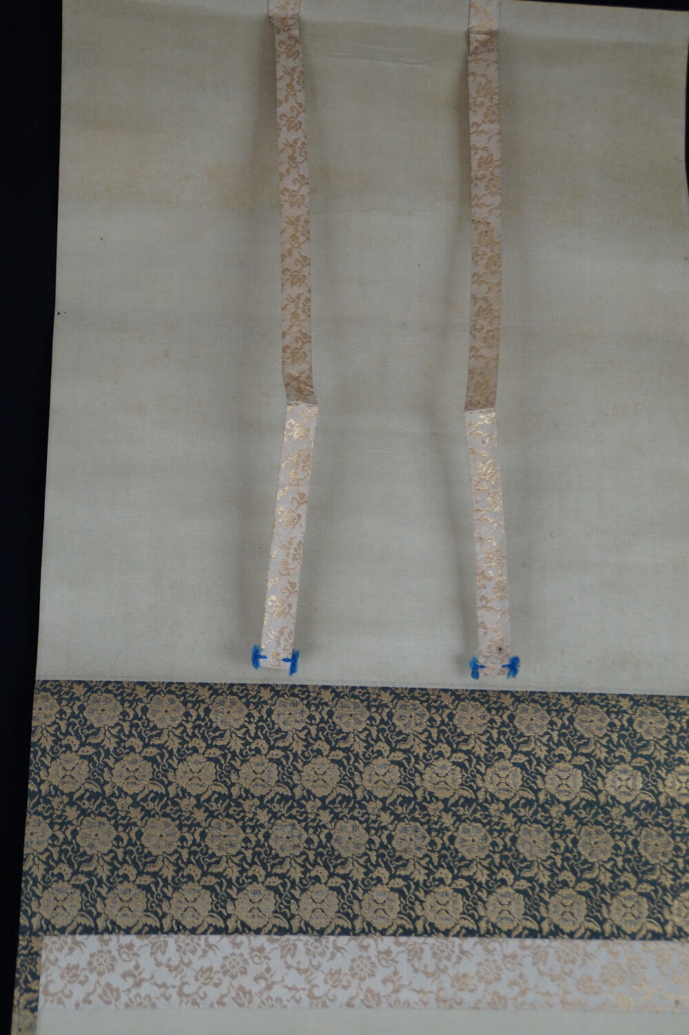 Detail view of the cream-colored silk mounting with binding cords on the hanging scroll House in the Fog on a Mountain Slope by Hashimoto Gaho