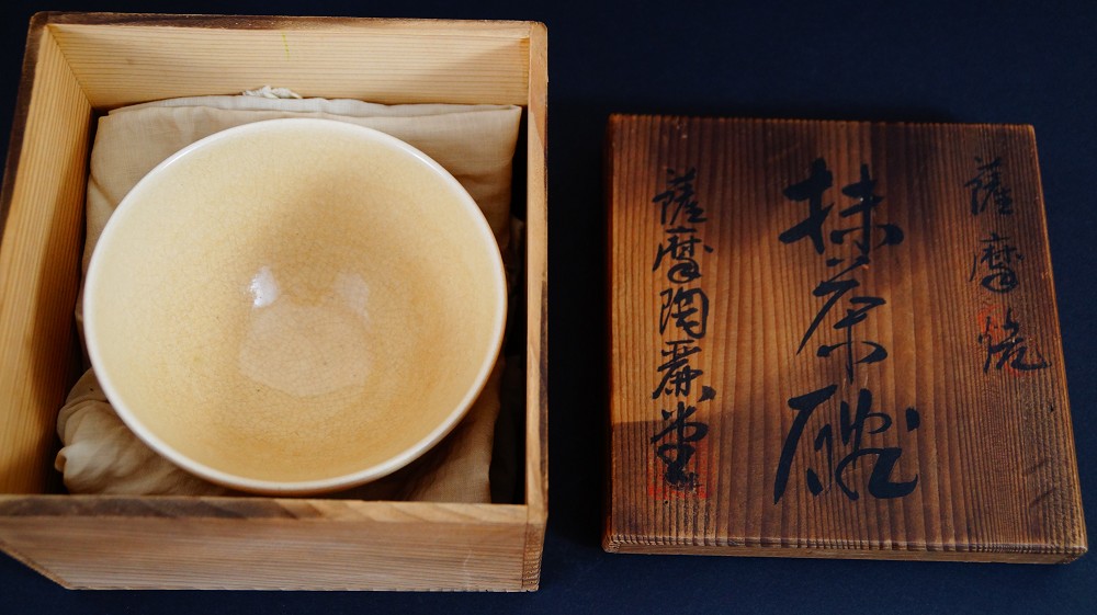 Chawan made of Satsuma ware by Gyokusen Nozaki wrapped in cloth in the opened storage box with the inscription Satsuma-yaki Matcha Chawan