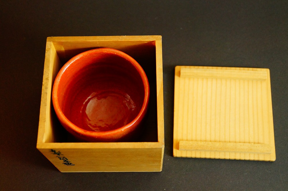 Chawan aus Raku-Keramik in der geoeffneten Aufbewahrungsbox neben dem Deckel