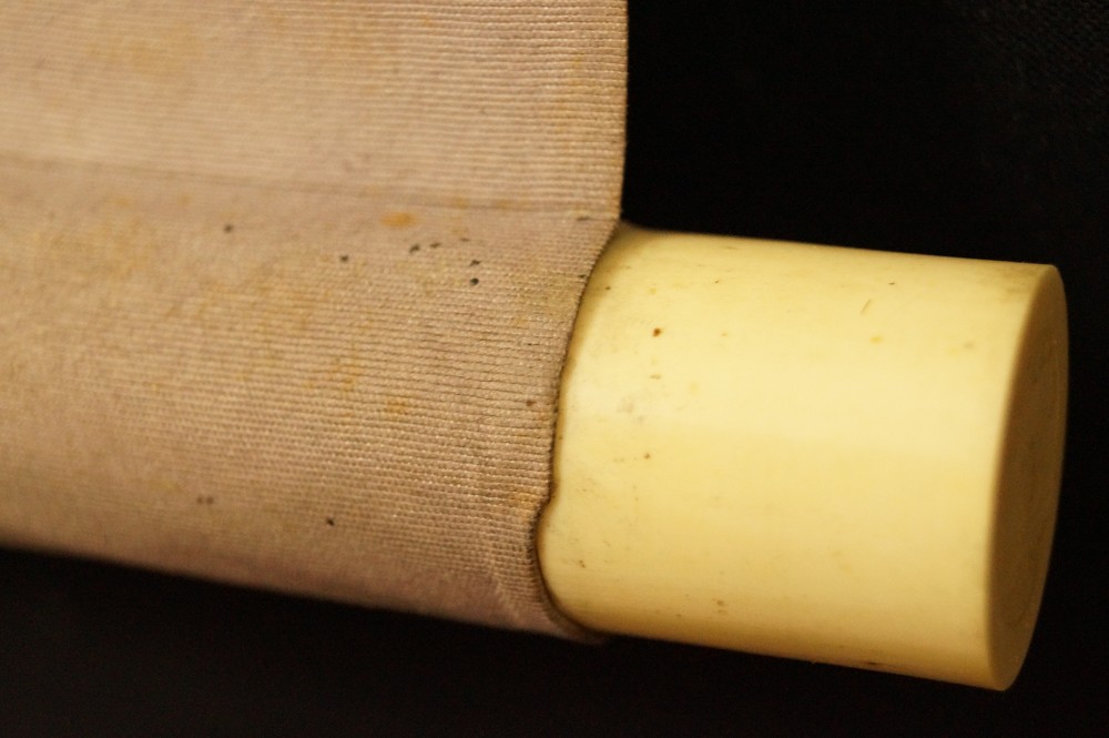 Ivory-colored roller knob with silk fabric scroll detail