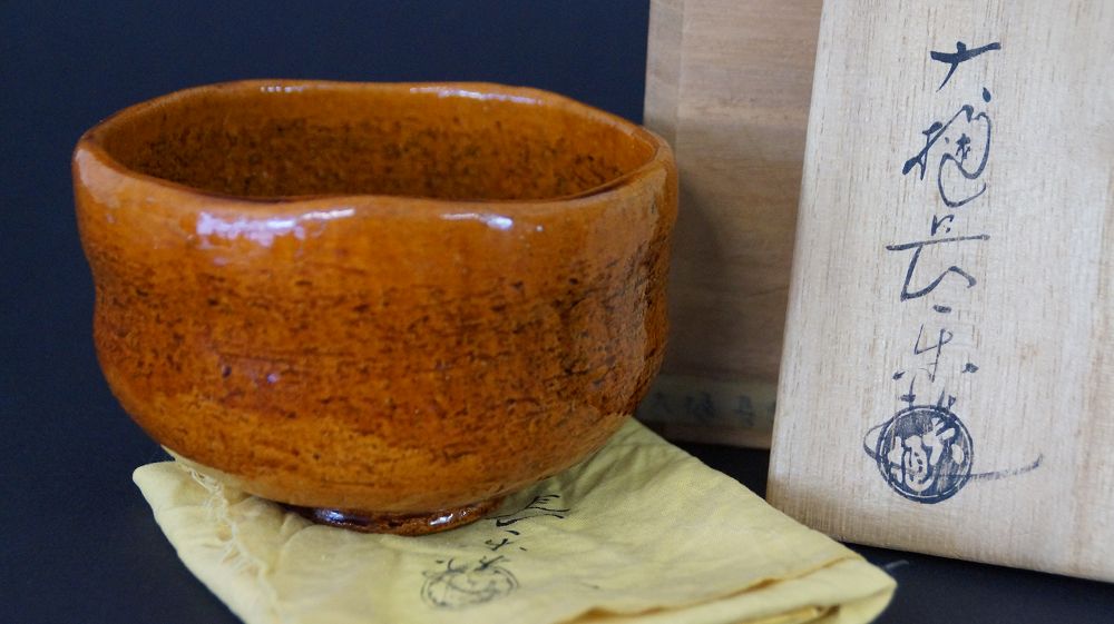 Chawan tea bowl made of Ohi ware next to the signed storage box