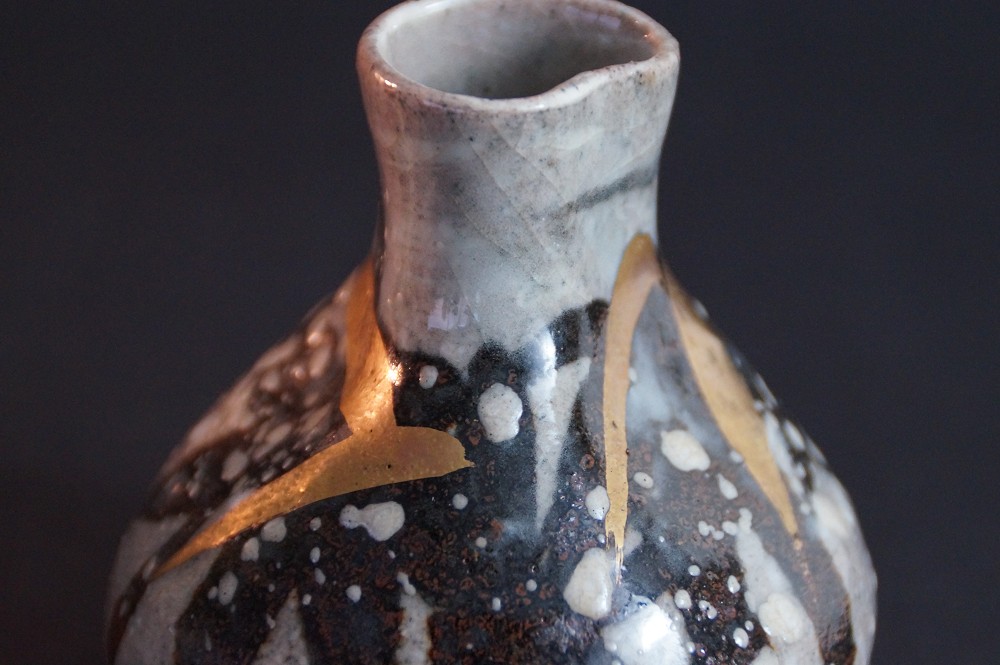 Close-up of the flared mouth with golden brushstrokes on dark glaze