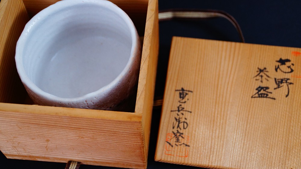 Chawan made of Shino ware by Jyuzo Sato next to the opened lid of the storage box with the ink inscription Shino Chawan