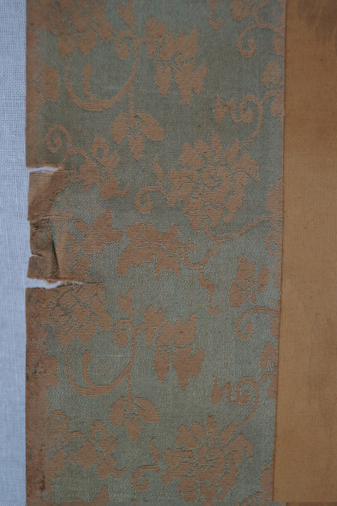 Landscape with bridge and mountain village close-up of the turquoise fabric mounting with blossom vines mounting detail