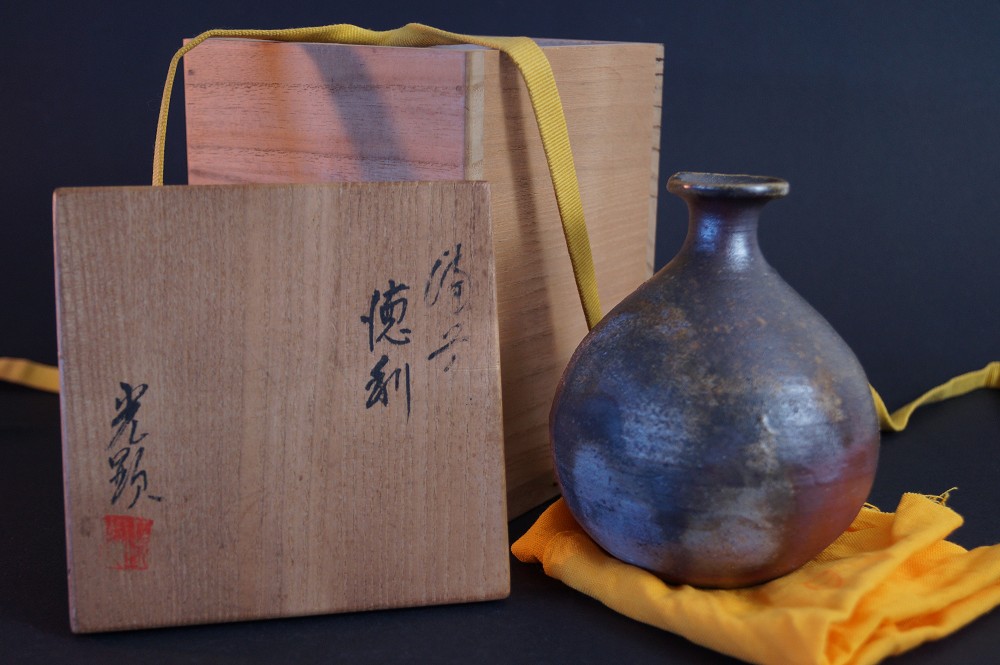 The sake bottle in front of the signed storage box with red seal