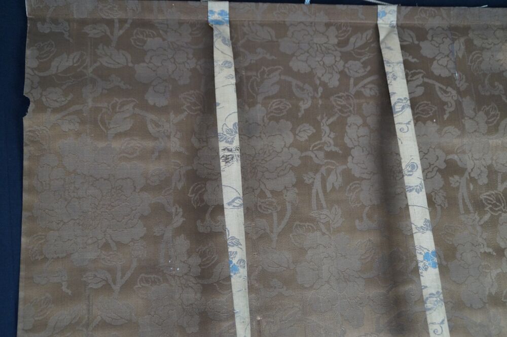 Detail view of the silk mounting with brown floral pattern and hanging cords of the Kakemono Cranes in Flight over Bamboo