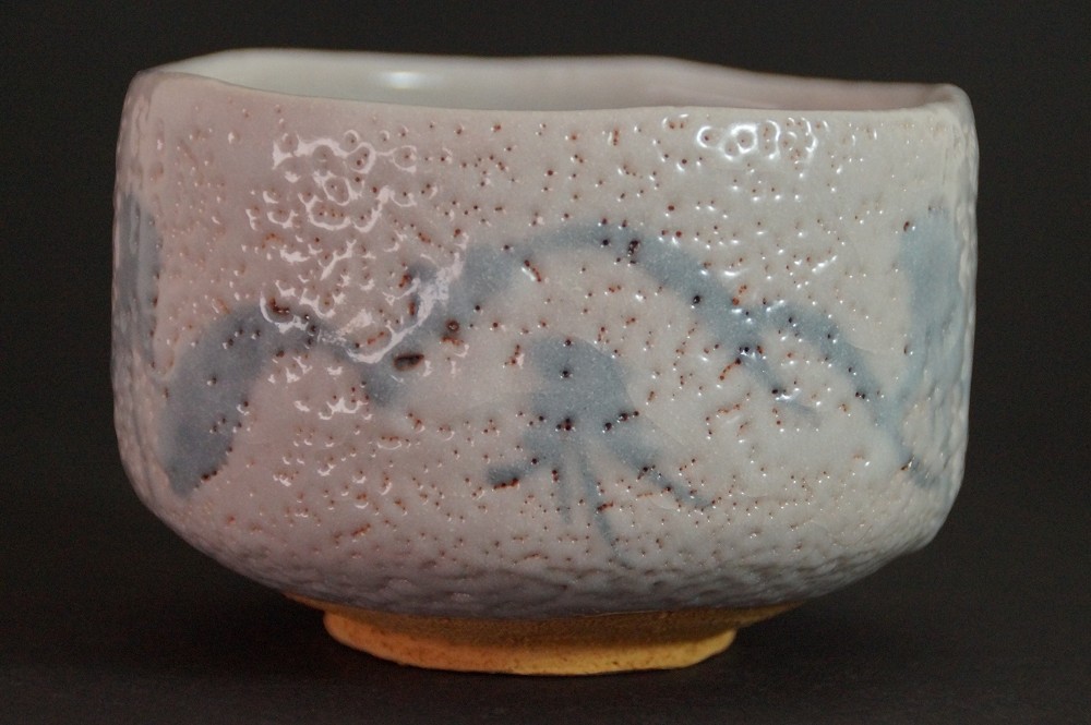 Side view of the chawan with cream-white Shino glaze in front of the storage box