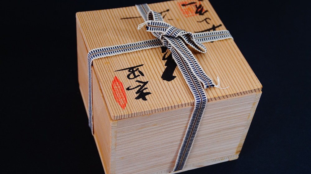 Closed storage box of the chawan made of Shino ware by Kazufumi Wada with ink inscription and red artist's seal, tied with a patterned cord