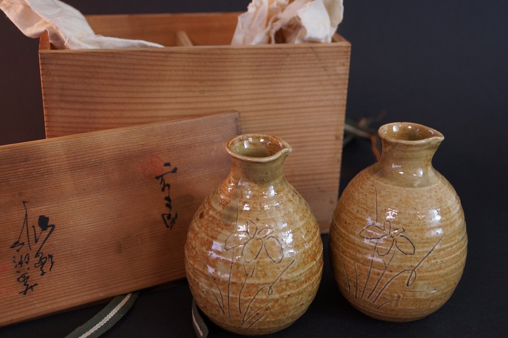 The two sake bottles in front of the opened storage box with calligraphy