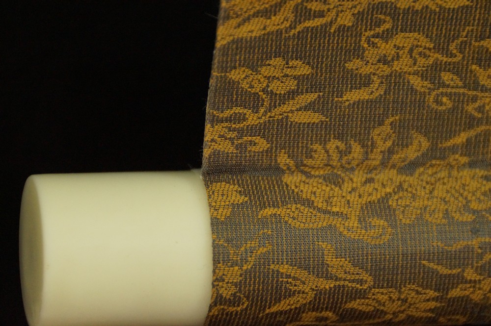 Close-up of the light-colored jikusaki at the end of the scroll roller