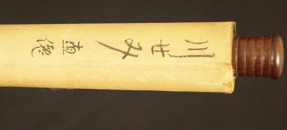 Scroll rod end with dark grip knob and inscribed paper Scroll Detail