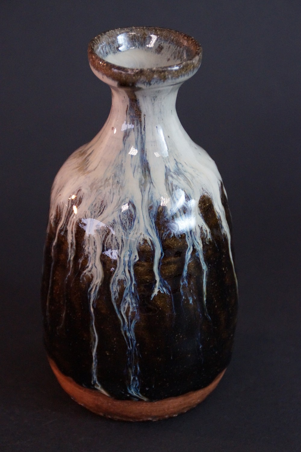 Side view of the tokkuri with flowing white glaze over dark clay body