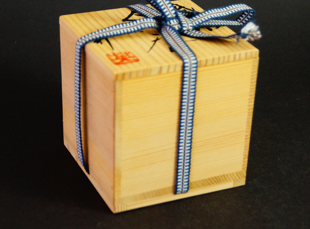 Closed storage box made of kiri wood with blue and white cord tie and red artist's seal