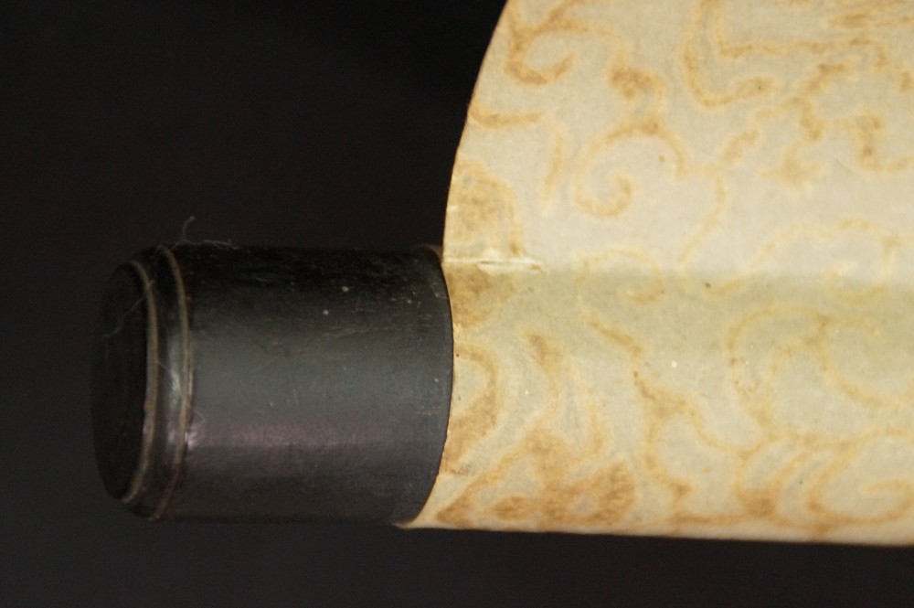 Close-up of the dark lacquered jikusaki at the end of the scroll