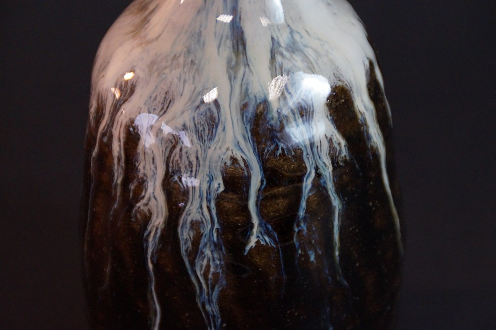 Close-up of the drip-shaped white glaze running down on a dark ground