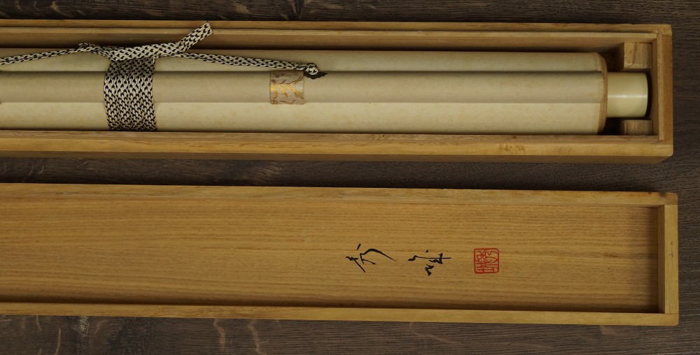 Rolled-up hanging scroll in an opened wooden box with a cord