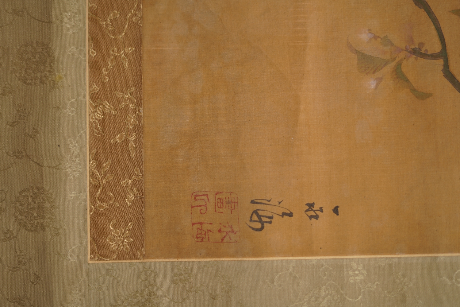 Detail view of the artist's signature and the red seal next to a cherry blossom branch in the hanging scroll songbird on blooming cherry branch