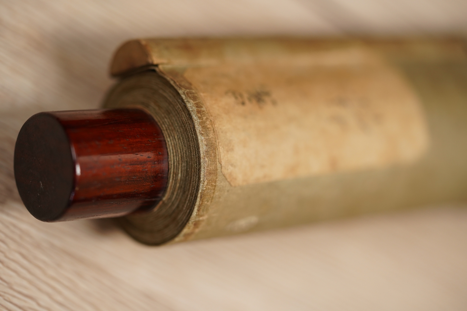 Detail view of the scroll end with dark red lacquer knob and cream-colored silk of the Kakemono Songbird on Blooming Plum Tree