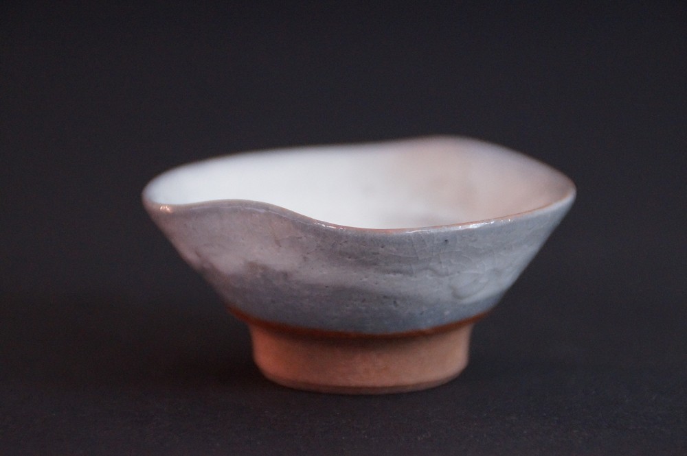 Frontalansicht der handgetoepferten Seto Sake Schale mit welligem Rand