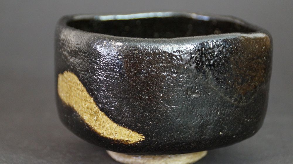 Additional view of the chawan made of Raku ware with diagonal gold-colored glaze stripe