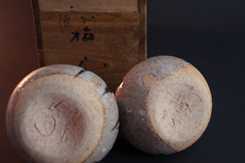 Close-up of the two foot bases with incised potter's marks in front of the storage box
