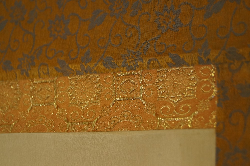 Corner detail of the gold-colored brocade mounting with floral pattern Mounting Detail