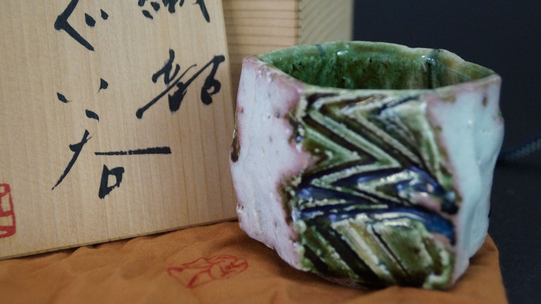 Guinomi sake cup made of Oribe ware next to the signed storage box with red artist's seal