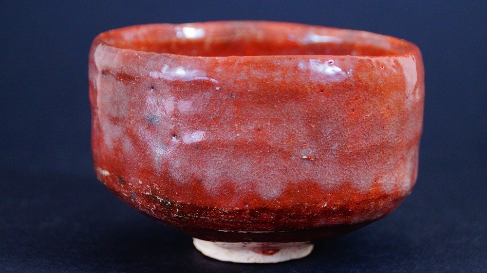 Chawan made of Raku ware by Sairi Hotoku in front view with bright red glaze