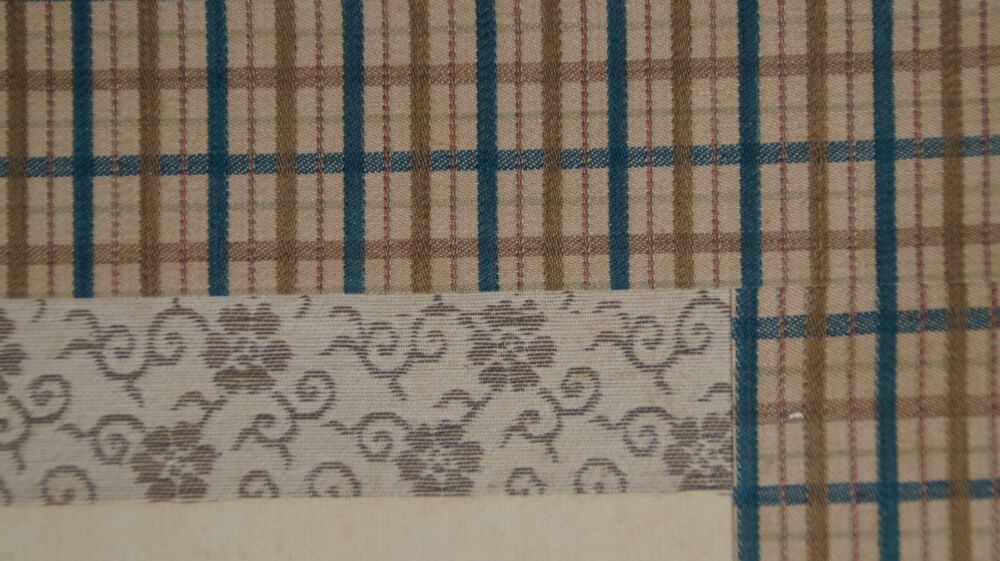 Detail view of the checkered silk mounting with cream-colored picture border of the hanging scroll Young Woman in Front of Her Kimono Cabinet