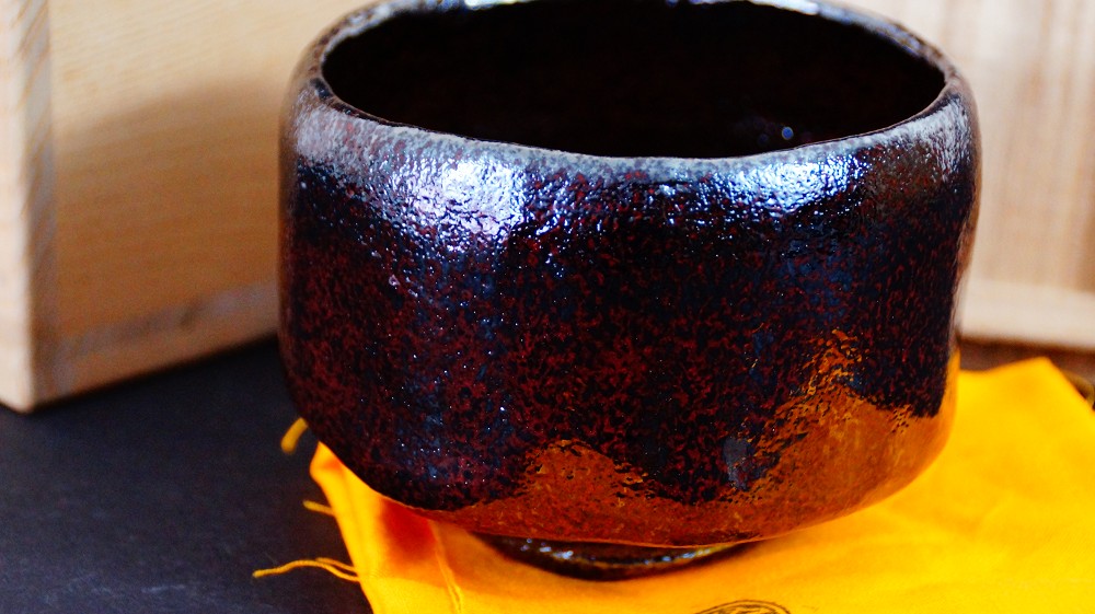 Chawan Made of Raku Ware by Shoraku Sasaki Next to the Storage Box on Orange Cloth