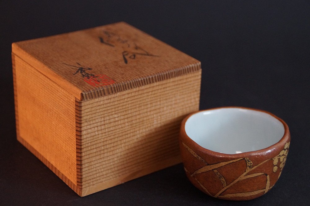 The sake cup next to the signed storage box with calligraphy and red seal