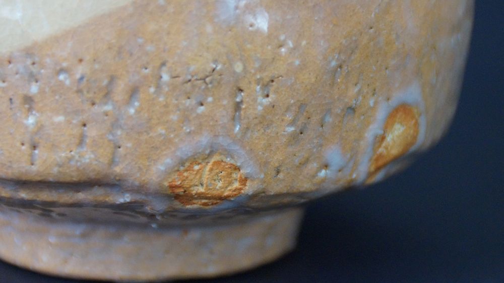 Extreme close-up of the textured glaze structure with orange specks of the Chawan tea bowl made of Raku ware