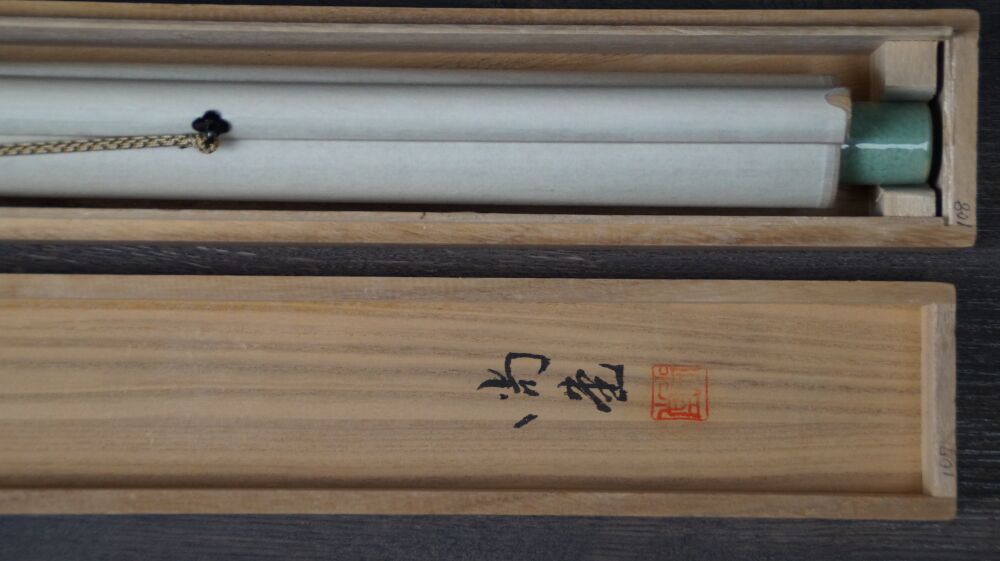 Opened storage box with inscription and rolled-up kakemono Songbird on Blooming Plum Tree