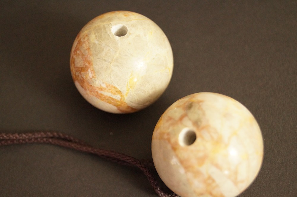 Two orange marbled stone spheres with drilled holes stone close-up 1
