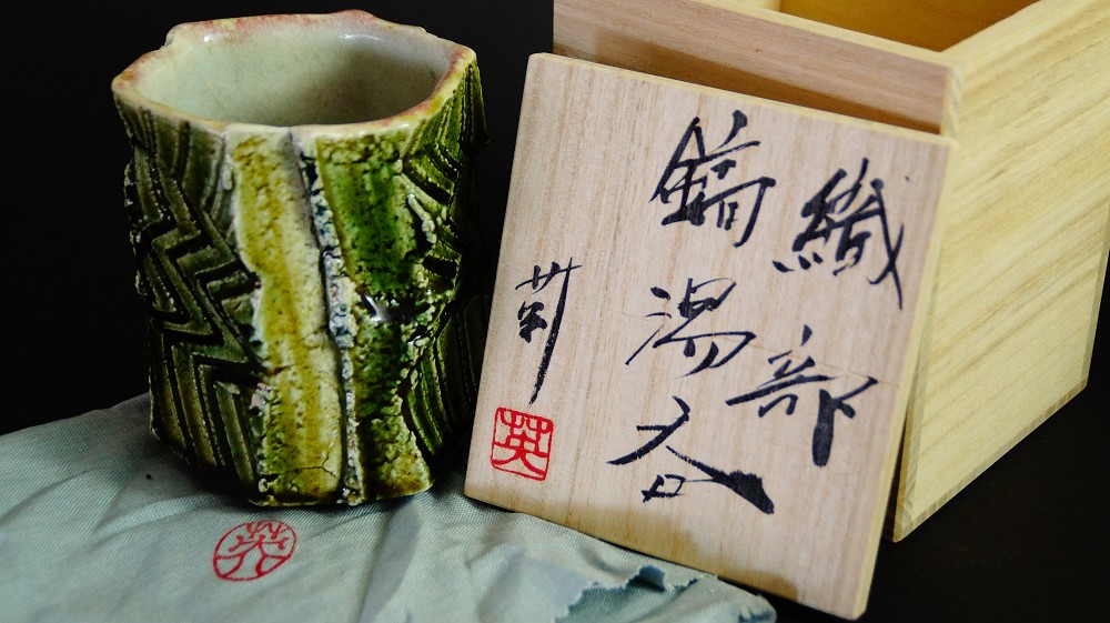 Yunomi tea bowl made of Oribe ware by Kawachi Hidetoshi front view with storage box