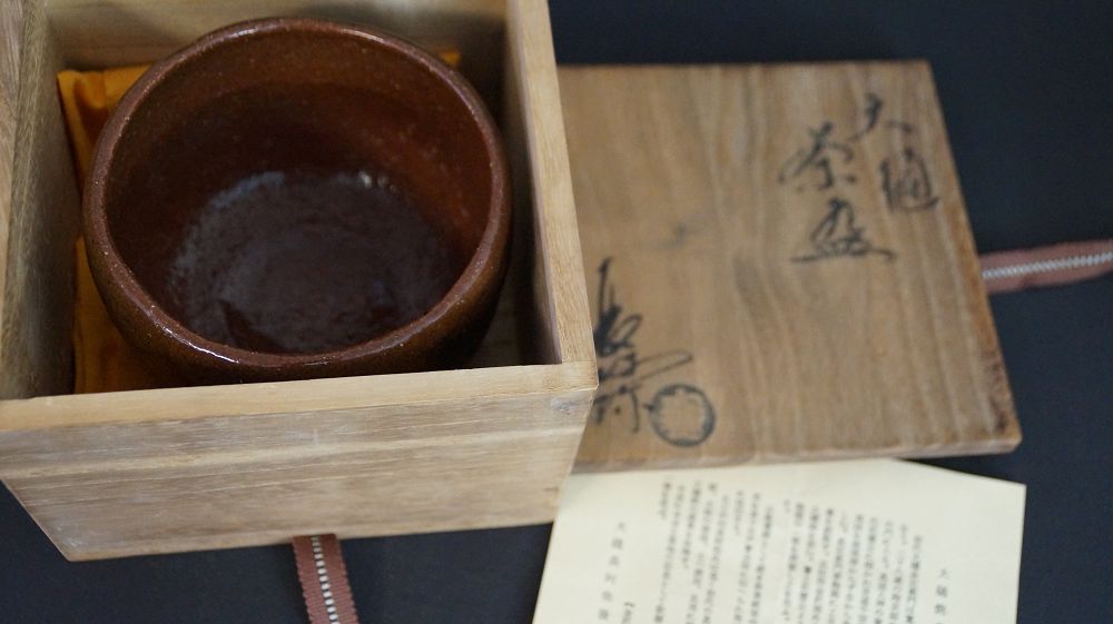 Chawan made of Ohi ware in the opened storage box next to the signed box lid and the certificate of authenticity