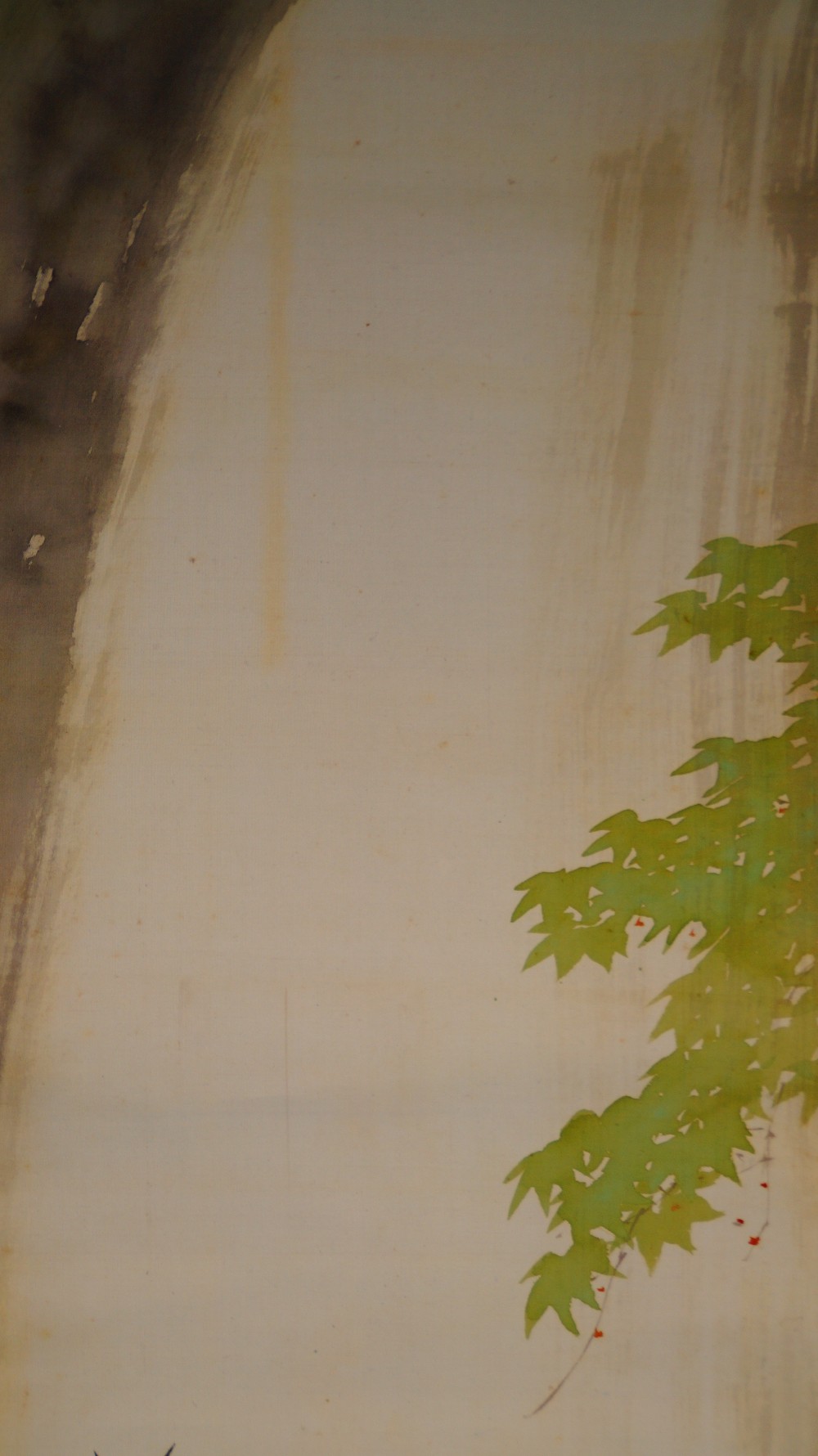 Close-up of the waterfall with a maple branch at the right edge of the image