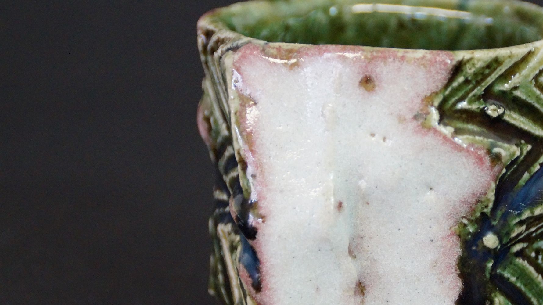 Close-up of the rim with pink-green glaze gradient of the guinomi sake cup made of Oribe ware